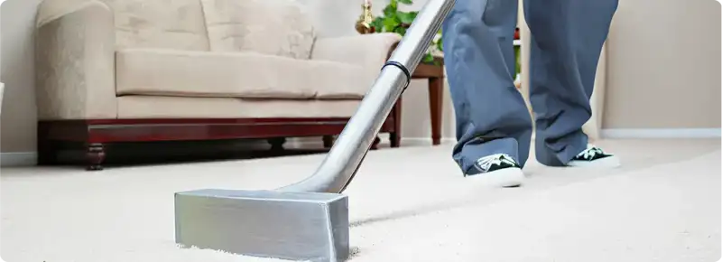 Carpet cleaning technician using a hot-water extraction wand on a light-colored carpet in a living room, Los Angeles, CA.